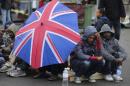 Eritrean migrants take cover from the rain under an umbrella during the daily food distribution at the harbour in Calais