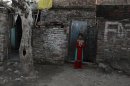 A girl stands beside her house at a slum in Islamabad