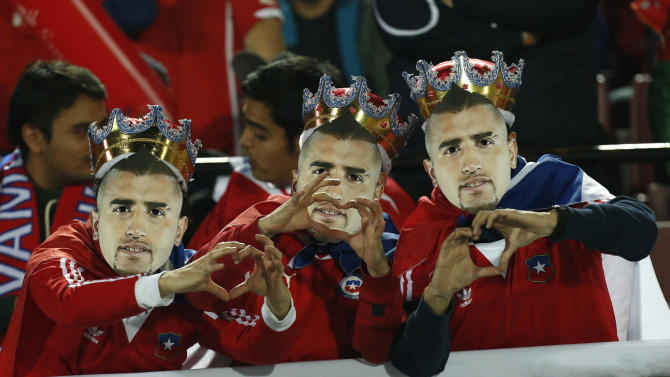 Chile soccer fans wearing crowns and masks of player Arturo Vidal, known by fans as &quot;Rey Arturo,&quot; or King Arthur, gesture heart signs as they wait for the start of a Copa America Group A soccer match between Chile and Bolivia at El Nacional stadium in Santiago, Chile, Friday, June 19, 2015. (AP Photo/Luis Hidalgo)