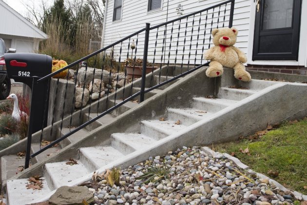 A lone teddy bear sits on the steps of the home where three children, their uncle, and their grandmother were found dead inside a garage Monday in what appears to be a murder-suicide amid a custody dispute in Toledo, Ohio, Tuesday, Nov. 13, 2012. (AP Photo/Rick Osentoski)