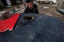 A member of the security forces looks at a damaged car in front of the My Fair Lady restaurant in Mosul, Iraq