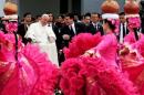 Pope Francis talks with Paraguayan President Cartes as dancers perform after his arrival at the international airport in Asuncion