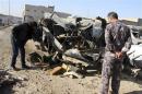 An Iraqi policeman looks at a damaged vehicle after a car bomb attack in Baghdad
