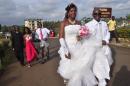 In this photo taken on Saturday, Nov. 15, 2014, an unidentified couple that just got married walk in a park used for wedding photography in the city of Monrovia, Liberia. Many have postponed their weddings in October as Ebola ravaged Liberia’s capital and the government warned people to avoid large gatherings. Weddings are full of kissing and hugging and just one unknowingly sick person could infect dozens. Now in a sign that daily life is returning as cases fall, the couple tied the knot without waiting any longer. (AP Photo/ Abbas Dulleh)
