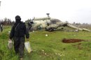 This citizen journalism image provided by Edlib News Network, ENN, which has been authenticated based on its contents and other AP reporting, shows a Syrian rebel carrying food supplies, as he walks in front of a damaged helicopter at Taftanaz air base that was captured by the rebels, in Idlib province, northern Syria, Friday Jan. 11, 2013. Islamic militants seeking to topple President Bashar Assad took full control of a strategic northwestern air base Friday in a significant blow to government forces, seizing helicopters, tanks and multiple rocket launchers, activists said. (AP Photo/Edlib News Network ENN)