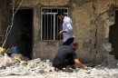 Iraqis inspect the site of two roadside bombs near a house in Madaen