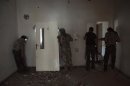 Free Syrian Army fighters peek through holes in a wall at forces loyal to Syria's President Bashar al-Assad in Deir al-Zor