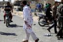 A man with his clothes stained with blood walks at a site hit by what activists said was an airstrike by forces loyal to Syria's President al-Assad, in Kafruma village in the southern province of Idlib