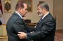 Egypt's new president-elect Mohamed Morsi (R) shake hands with Prime Minister Kamal al-Ganzuri