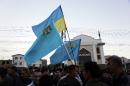 Crimean Tatars hold a Ukrainian and Tatar flags as they attend a memorial ceremony marking the 70th anniversary of the deportation of Tatars from Crimea, near a mosque in Simferopol on May 17, 2014