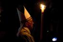 Pope Francis holding a tall, lit, white candle, enters a darkened St. Peter's Basilica to begin the Easter vigil service, at the Vatican, Saturday, April 19, 2014. (AP Photo/Alessandra Tarantino)