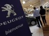 A salesman speaks with a customer next to a Peugeot car at a dealership in Marseille