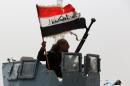 A member of the Iraqi anti-terrorism forces waves the national flag in celebration after securing a checkpoint from Sunni militants in the village of Badriyah, on August 19, 2014