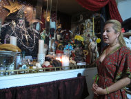In this Feb. 12, 2013 photo, Arely Vazquez Gonzalez, a Mexican immigrant and transgender woman, is shown with her alter to La Sante Muerte at her Queens, NY apartment. La Santa Muerte, an underworld saint most recently associated with the violent drug trade in Mexico, now is spreading throughout the U.S. among a new group of followers ranging from immigrant small business owners to artists and gay activists. (AP Photo/Russell Contreras)