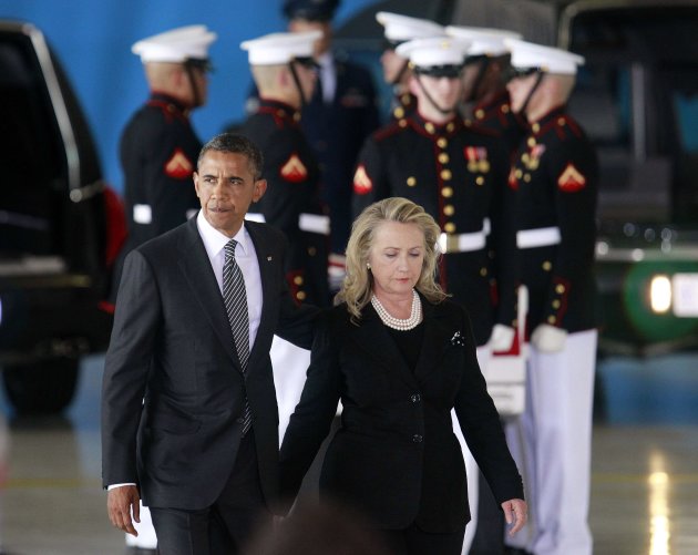 U.S. President Barack Obama walks with Secretary of State Hillary Clinton past the flag-draped transfer case of one of four Americans who died this week in Libya, during a transfer of remains ceremony
