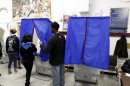 Poll worker assists voter with voting booth curtain before voting during U.S. presidential election at Penrose recreation center in Philadelphia