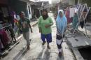 In this Tuesday, Oct. 21, 2014 photo, tsunami survivor Jamaliah, center, walks with Raudhatul Jannah, right, and Arif Pratama, whom she believes to be her two children separated with her when the village they lived in was hit by the killer waves in 2004, in their neighborhood in Meulaboh, Aceh province, Indonesia. Although there has been no DNA test the parents are convinced that the children belong them. (AP Photo/Binsar Bakkara)