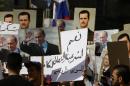 Syrians hold up portraits of President Bashar al-Assad and his Russian counterpart Valdimir Putin near the Russian embassy in Damascus, just before two rockets struck the embassy compound on October 13, 2015