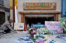 A woman places a candle near flowers and messages outside the mountain guides bureau in tribute to Herve Gourdel in Saint-Martin-Vesubie
