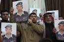 Relatives of Islamic State captive Jordanian pilot al-Kasaesbeh hold his poster as they take part in a rally in his support at the family's headquarters in the city of Karak