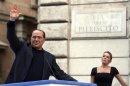 Former Italian Prime Minister Silvio Berlusconi waves to supporters as his girlfriend Francesca Pascale looks on during a rally to protest his tax fraud conviction, outside his palace in central Rome