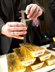 A bank employee meassures a gold ingot during a press conference at the German central bank in Frankfurt, Germany, Wednesday Jan. 16, 2013. Germany's central bank is to bring back home some US $36 billion ( 27 billion euro) worth of gold stored in the United States and France. The Bundesbank said in a statement Wednesday that it will repatriate all 374 tons of gold it had stored in Paris by 2020. An additional 300 tons - equivalent to 8 percent of the Bundesbank's total reserves worth about US$183 billion _ will also be shipped from New York to Frankfurt. Frankfurt will hold half of Germany's 3,400 tons of gold by 2020, with New York retaining 37 percent and London storing 13 percent. The move follows criticism from Germany's independent Federal Auditors' Office last year bemoaning the central bank's oversight of gold reserves abroad. (AP Photo/dpa/ Frank Rumpenhorst)