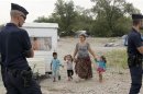 French CRS police stand in an illegal camp housing about 114 Roma, referred to as "Gens du Voyage", as they start to evacuate families and remove their caravans in Saint-Priest