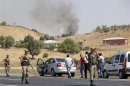Turkish soldiers take security measures on a main road which connects eastern Turkish cities Bingol and Mus, as smoke rises from a burning vehicle in the background, in Bingol province