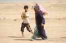 Displaced Iraqis who fled the government's operation against the Islamic State group in the city of Fallujah carry basic food items on June 20, 2016 in a camp in Khaldiyeh