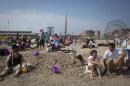People sit on the beach at Coney Island in the Brooklyn borough of New York