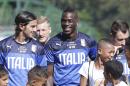 Italy's Alberto Aquilani, left, and Mario Balotelli pose for photos with children at their training session in Mangaratiba, Brazil, Tuesday, June 17, 2014. Italy plays in group D at the soccer World Cup. (AP Photo/Antonio Calanni)