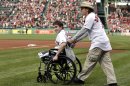 FILE - Boston Marathon bombing survivor Jeff Bauman, left, is wheeled out by Carlos Arredondo, the man who helped save his life, to throw out the ceremonial first pitch at Fenway Park in a Tuesday, May 28, 2013 file photo, prior to a baseball game between the Boston Red Sox and the Philadelphia Phillies, in Boston. Bauman is working on a memoir with Grand Central Publishing to be titled 