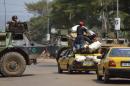A taxi passes a French military armoured vehicle on January 9, 2014 in Bangui