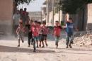Children flash victory signs as they play in Manbij, in Aleppo Governorate