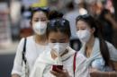 A tourist wearing a mask to prevent contracting Middle East Respiratory Syndrome (MERS) uses her mobile phone at Myeongdong shopping district in central Seoul