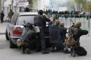 Pro-Russian armed men take cover behind a car near the local police headquarters in Luhansk