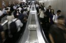 Commuters ride escalators at a subway station in Tokyo