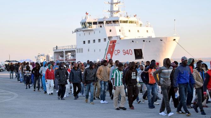 Shipwrecked migrants disembark from a rescue vessel as they arrive in the Italian port of Augusta in Sicily on April 16, 2015