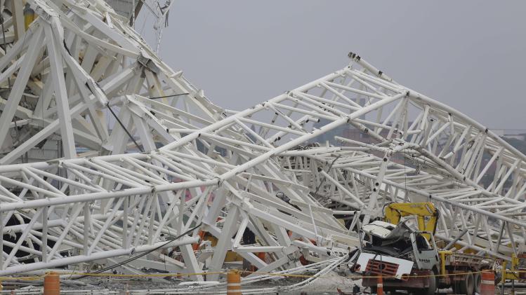 A collapsed metal structure sits on the ground at Itaquerao Stadium in Sao Paulo, Brazil, Wednesday, Nov. 27, 2013. The accident that resulted in the death of at least two workers, occurred when a construction crane crashed into a 500-ton metal structure that in turn cut through the outer walls of the venue, destroying rows of seats and slamming into a massive LED panel that runs across the stadium's facade. The stadium is slated to host the 2014 World Cup opener. (AP Photo/Nelson Antoine)