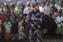 An armed police officer guards as Muslim refugees stand behind him at a refugee camp in Sittwe, capital of Rakhine State, western Myanmar, Saturday, Oct. 27, 2012. Western Myanmar appeared calm Saturday after almost a week of deadly ethnic strife, a government spokesman said as human rights groups called for action to end the violence that one said it has documented with satellite imagery. Rakhine state spokesman Win Myaing there were no immediate reports of fresh clashes between the Buddhist Rakhine and the Muslim Rohingya communities. (AP Photo/Khin Maung Win)
