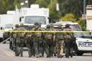 A SWAT team walks down the street near Adams Elementary School searching for a gunman on Wednesday, March 18, 2015 in Mesa, Ariz. A gunman wounded at least four people across multiple locations in the Phoenix suburb. The first shooting happened at a motel, and people were also wounded at a restaurant and nearby apartment complexes. (AP Photo/The Arizona Republic, Rob Schumacher) MARICOPA COUNTY OUT; MAGS OUT; NO SALES