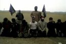 Still frame from video obtained from a social media website shows three rebels, two of them carrying Jabhat al-Nussra flags, stand behind a row of 11 kneeling men prior to executing them in what is said to be Deir al-Zor