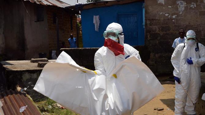 Trabalhadores da saúde da Libéria Cruz Vermelha, vestindo roupas de proteção, levar o corpo de um bebê de 18 meses de idade, vítima do vírus Ebola em 12 de setembro, 2014