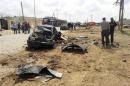 Men stand next to car damaged after explosion exploded outside Libyan army base in eastern city of Benghazi