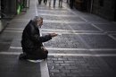 A man begs for alms in a street, in Pamplona, northern Spain, Tuesday, Oct. 30, 2012. Spain's National Statistics Institute says Tuesday that the country's economy contracted 0.3 percent in the third quarter from the previous three month period. Spain is in a double-dip recession and has a 25 percent unemployment rate. Prime Minister Mariano Rajoy said Monday the country has no immediate need to ask for outside aid to help deal with its debts. (AP Photo/Alvaro Barrientos)