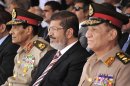 In this image released by the Egyptian President, Egyptian Field Marshal Gen. Hussein Tantawi, left, and new President Mohammed Morsi, center, attend a medal ceremony, at a military base east of Cairo, Egypt, Thursday, July 5, 2012. A Palestinian official says Gaza's prime minister will head to Cairo within the next two weeks to meet with Egypt's new Islamist president, who has close ties with the territory's Hamas rulers. (AP Photo/Mohammed Abd El Moaty, Egyptian Presidency)