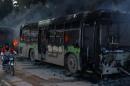 A man on a motorcycle drives past burning buses while en route to evacuate ill and injured people from the besieged Syrian villages of al-Foua and Kefraya, after they were attacked and burned, in Idlib province