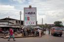 People walk in front of a poster warning against the deadly Ebola virus in Freetown, October 4, 2014