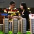 A salesperson talks to a customer behind models of a residential compound at a real estate exhibition in Wuxi