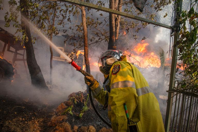 This handout photo taken on January 12, 2014 and supplied by Australia's Department of Fire and Emergency Services (DFES) shows a firefighter working to contain wildfires in the Stoneville area, a suburb near Perth in Western Australia